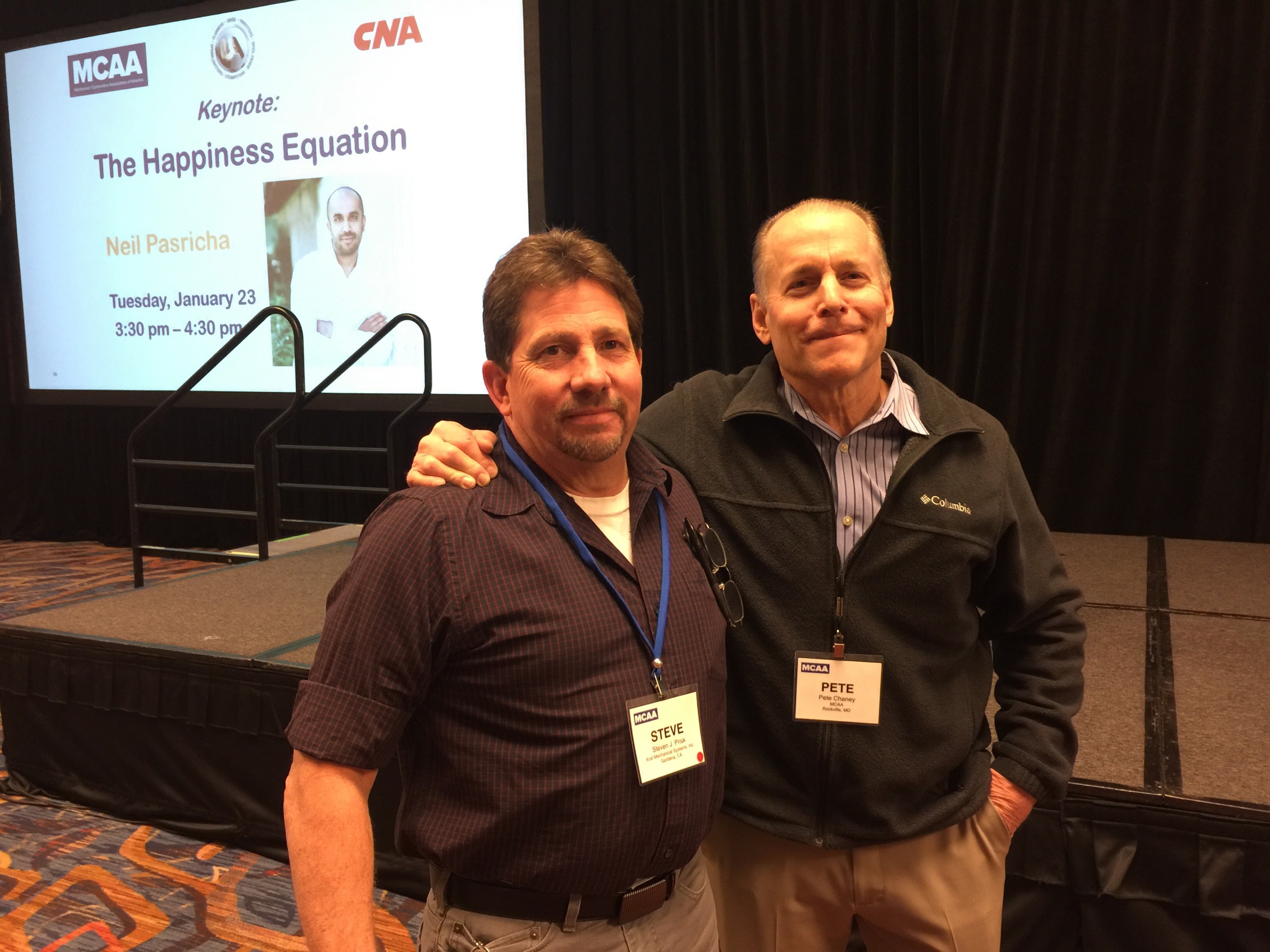 Two men posing in front of conference stage