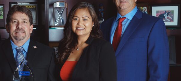 Three professionals posing with award in office