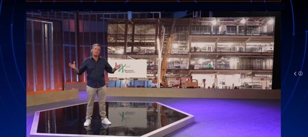 Presenter on hexagonal stage with industrial backdrop